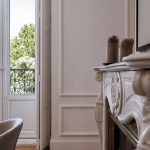 Detalle de chimenea de mármol clásica y balcón con vistas al arbolado — fotografía inmobiliaria en Chueca, frente a la Iglesia de Santa Bárbara