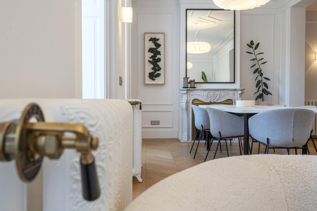 Comedor reformado con chimenea de mármol tallada y suelo de parquet en espiga — fotografía inmobiliaria en Chueca, Madrid