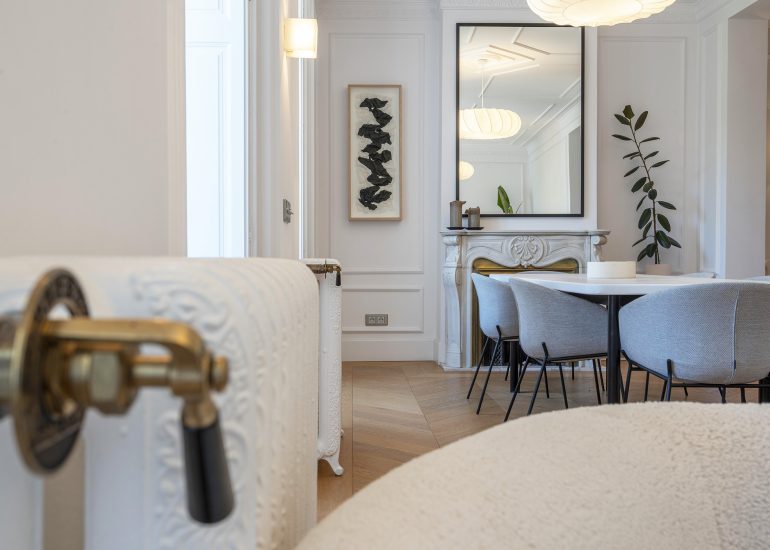 Comedor reformado con chimenea de mármol tallada y suelo de parquet en espiga — fotografía inmobiliaria en Chueca, Madrid