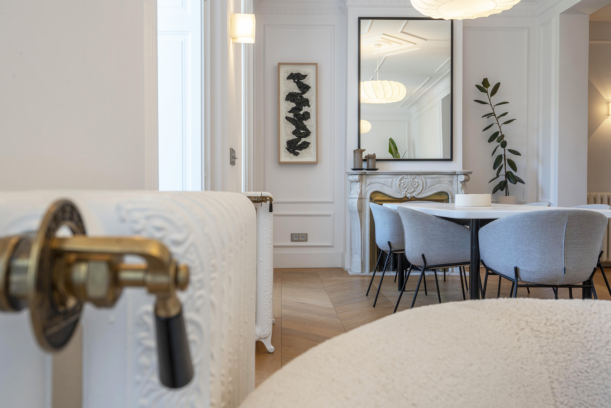 Comedor reformado con chimenea de mármol tallada y suelo de parquet en espiga — fotografía inmobiliaria en Chueca, Madrid