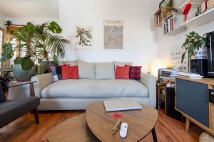 Salón con sofá y cojines de color, estanterías abiertas y luz natural — piso en venta en la calle Berruguete