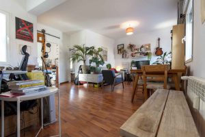 Salón comedor con suelo de madera, plantas y decoración vintage — piso en venta en Cuatro Caminos, Madrid