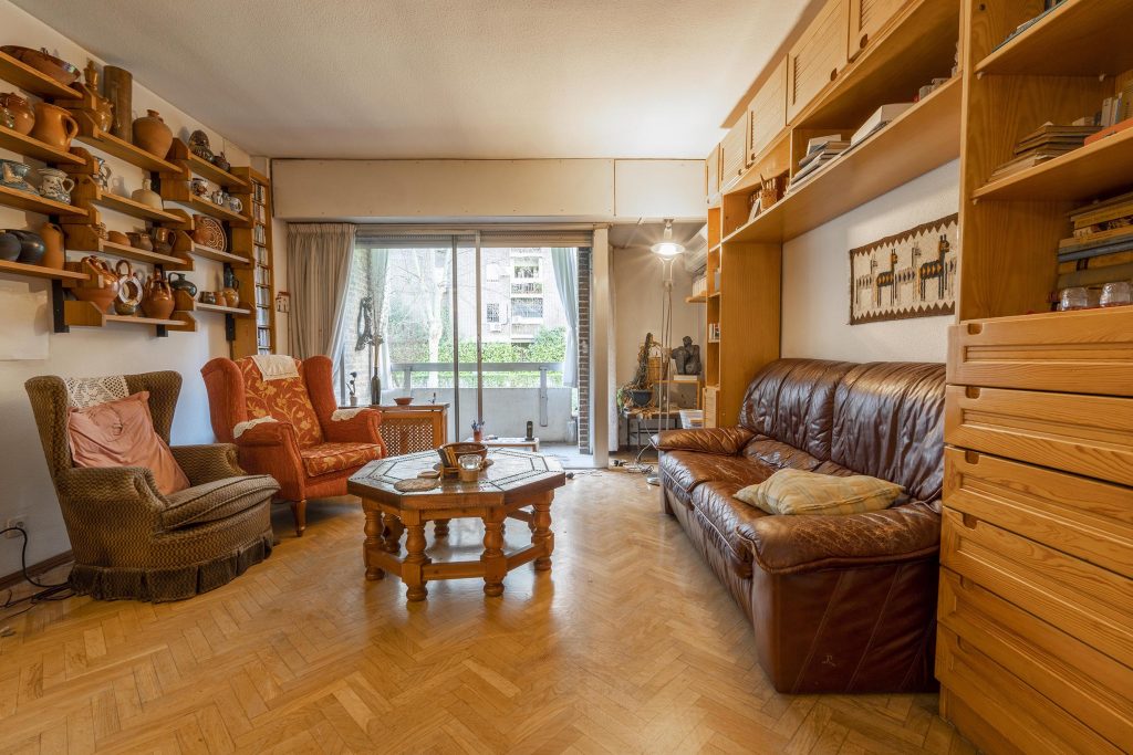 Salón original con muebles obsoletos y distribución pesada en piso del barrio La Estrella, Madrid